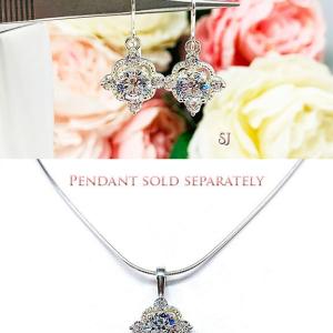 A photo composite showing dangle drop earrings and matching pendant necklace. The top photo shows a pair of silver dangle drop art deco style earrings set with round czs. There is one large round cz in the center, with four smaller czs mounted at the top, bottom and sides.  The cz dangles are hanging from ear wires. The bottom photo shows a silver single bail pendant set with the same style as the earrings hanging from a silver chain. The text 'Necklace sold separately' appears above it.