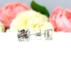 A pair of silver stud earrings with very light yellow or "near colorless" old mine cut cubic zirconia stones. The basket style soft claw prong earrings are on a white background with the left earring facing forward to showcase the 'chunky' facets and the right earring facing to the right displaying the center post and butterfly friction clasps.