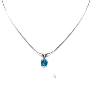 Sterling silver necklace featuring a natural 6mm round-cut swiss blue topaz pendant in a four-prong setting, shown on a sterling silver chain.