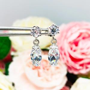A pair of silver drop earrings with marquise cut clear cubic zirconia stones. The top 6-prong stud earrings have a smaller round cubic zirconia stone at the top of the drop.