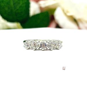 A sterling silver 5-stone ring featuring 3mm round precision faceted near colorless cubic zirconia stones in prong settings, displayed against a soft floral background.