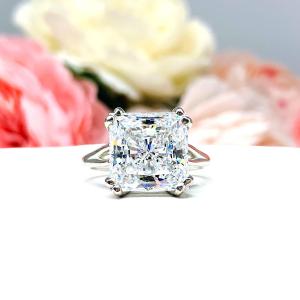 Elegant sterling silver engagement ring with an 11mm dazzling princess cut cubic zirconia, beautifully photographed against a romantic and timeless soft-focus floral background of pink and white blooms.