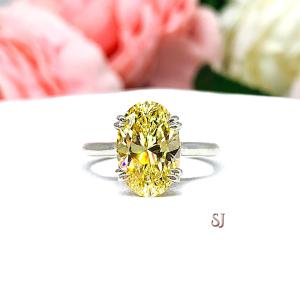 May include: A silver ring with a large, oval-shaped, yellow gemstone. The ring is set on a white background.