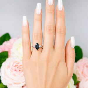 Sterling silver ring, featuring a 14x7mm marquise-cut London blue topaz flanked by two round moissanites, shown worn on the hand of a woman. Model image for size and styling reference — not a photo of the actual ring.