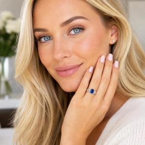 A woman wearing a sterling silver engagement ring featuring an emerald cut blue sapphire and 2.5mm round czs on the band. Shown with matching wedding band. Model image for size and styling reference — not a photo of the actual ring.