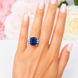 A woman's hand wearing a sterling silver engagement ring featuring a 12x10mm emerald cut blue sapphire and 2.5mm round czs on the band. Shown with matching wedding band. Model image for size and styling reference — not a photo of the actual ring.