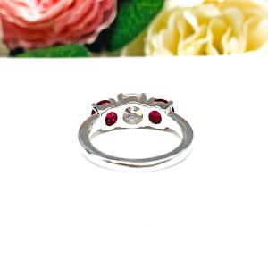 A sterling silver 3-stone ring with a 6mm round brilliant cut cubic zirconia center that radiates icy sparkle, flanked by two 5mm round deep red lab-created rubies.