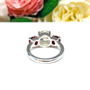 A sterling silver 3-stone ring with a 9mm near colorless round brilliant cut cubic zirconia center that radiates icy sparkle, flanked by two 5mm round deep red lab-created rubies.