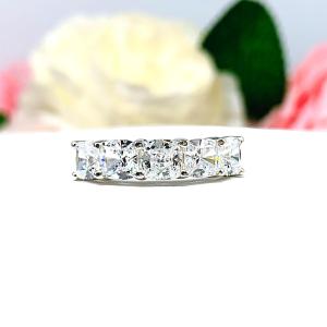 Five stone sterling silver ring featuring 5mm sparkling cushion cut cubic zirconias. Shown facing forward showcasing the "crushed ice"  faceting of the czs, shared prongs on each stone and highly polished band.