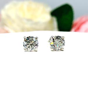 A pair of silver stud earrings set with round brilliant cut 'near colorless or 'G color' cubic zirconias.  The four prong basket earrings are on a white surface with both earrings facing slightly to the right to showcase the brilliant cutting of the czs, center post and butterfly friction clasps.