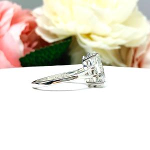 An elegant sterling silver engagement ring featuring a 13x9mm near colorless precision-cut pear cubic zirconia. Displayed on a white surface with a floral background.