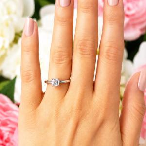 A woman's hand wearing a sterling silver 4-prong 5mm asscher cut DEF moissanite solitaire engagement ring. Model image for size and styling reference — not a photo of the actual ring.