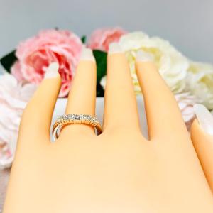 Mannequin hand with long white shimmery nails, displayed against a soft white-gray background with pink and white floral accents. The hand is wearing a sterling silver 5-stone curved wedding band featuring 3mm round precision faceted near colorless cz stones in prong settings.