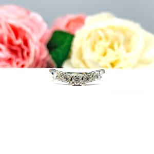 Sterling silver 5-stone curved wedding band featuring 3mm round precision faceted near colorless cubic zirconia stones in prong settings, displayed against a soft floral background.