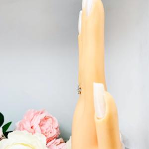 Mannequin hand with long white shimmery nails, displayed against a soft white-gray background with pink and white floral accents. The hand is wearing a sterling silver  cluster ring featuring four 3mm round light blue aquamarine gemstones.