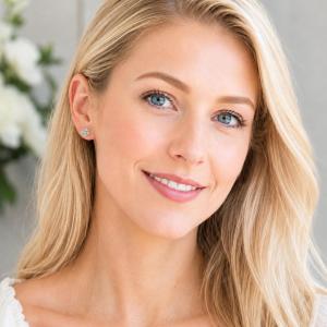 A woman wearing sterling silver cluster earrings featuring four 3mm round light blue aquamarine gemstones. Model image for size and styling reference — not a photo of the actual ring.