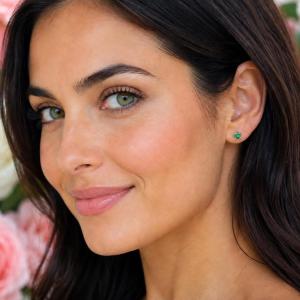 A woman wearing a pair of 4mm round natural emerald 14k yellow gold stud earrings. Model image for size and styling reference — not a photo of the actual earrings.