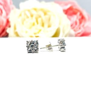 Sterling silver cluster earrings featuring four 3mm round light blue aquamarine gemstones. Displayed against a soft-focus floral background, the earrings sparkle with contrast and elegance.