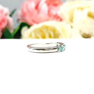 A sterling silver 5-stone band set with 3mm round sparkling aquamarine blue moissanites. Displayed on a white surface with a floral background.