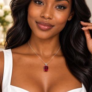 A woman wearing a sterling silver necklace featuring a 12x10mm emerald-cut lab-created ruby pendant in a 4-prong setting. Model image for size and styling reference — not a photo of the actual necklace.