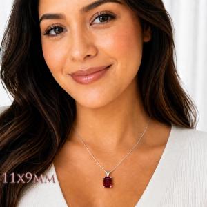 A woman wearing a sterling silver necklace featuring a 11x9mm emerald-cut lab-created ruby pendant in a 4-prong setting. Model image for size and styling reference — not a photo of the actual necklace.