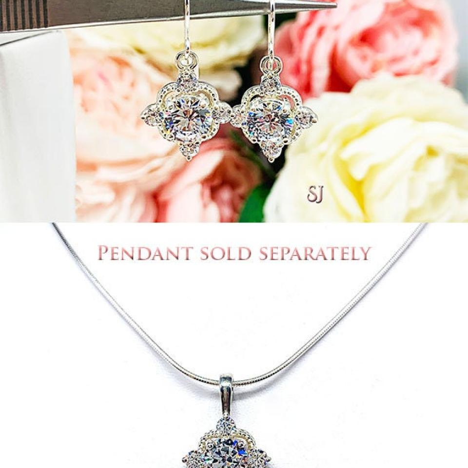A photo composite showing dangle drop earrings and matching pendant necklace. The top photo shows a pair of silver dangle drop art deco style earrings set with round czs. There is one large round cz in the center, with four smaller czs mounted at the top, bottom and sides.  The cz dangles are hanging from ear wires. The bottom photo shows a silver single bail pendant set with the same style as the earrings hanging from a silver chain. The text 'Necklace sold separately' appears above it.
