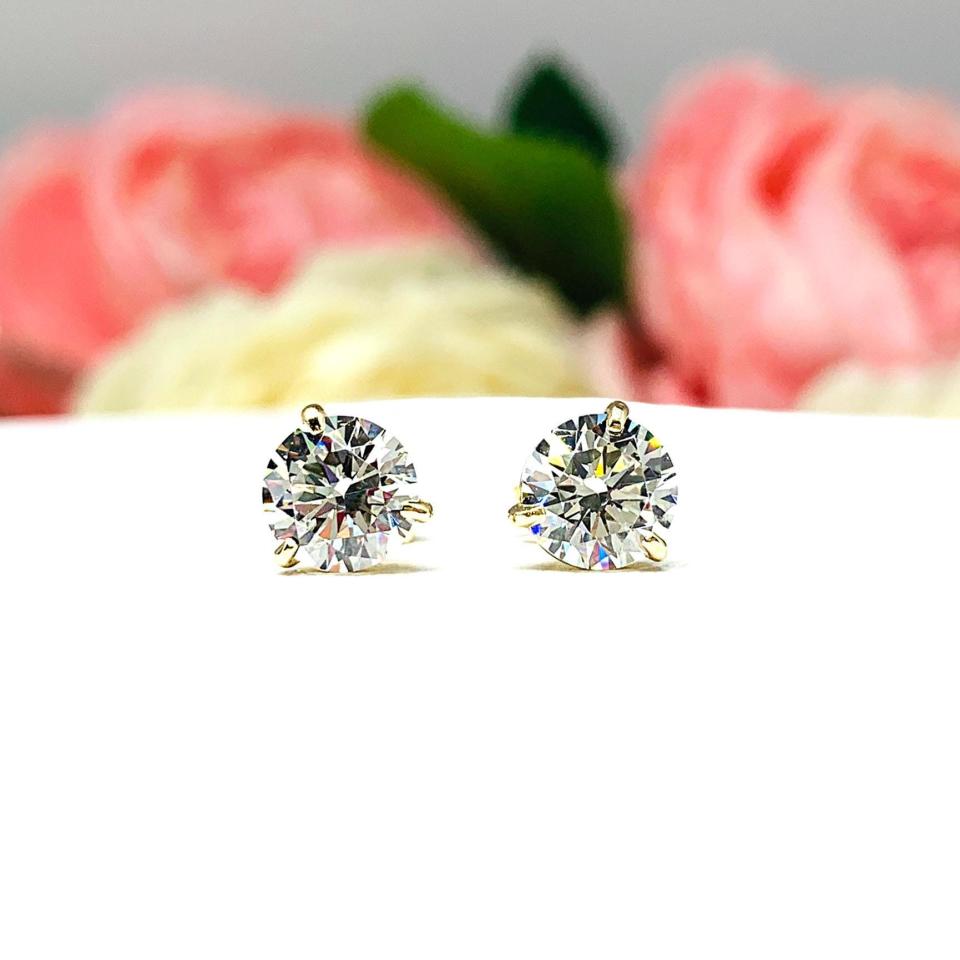 A pair of yellow gold 3-prong martini round 'near colorless' or 'G color' cubic zirconia stud earrings. The earrings are shown on a white background with both earrings facing forward showcasing the crisp faceting and clear clarity of the czs.