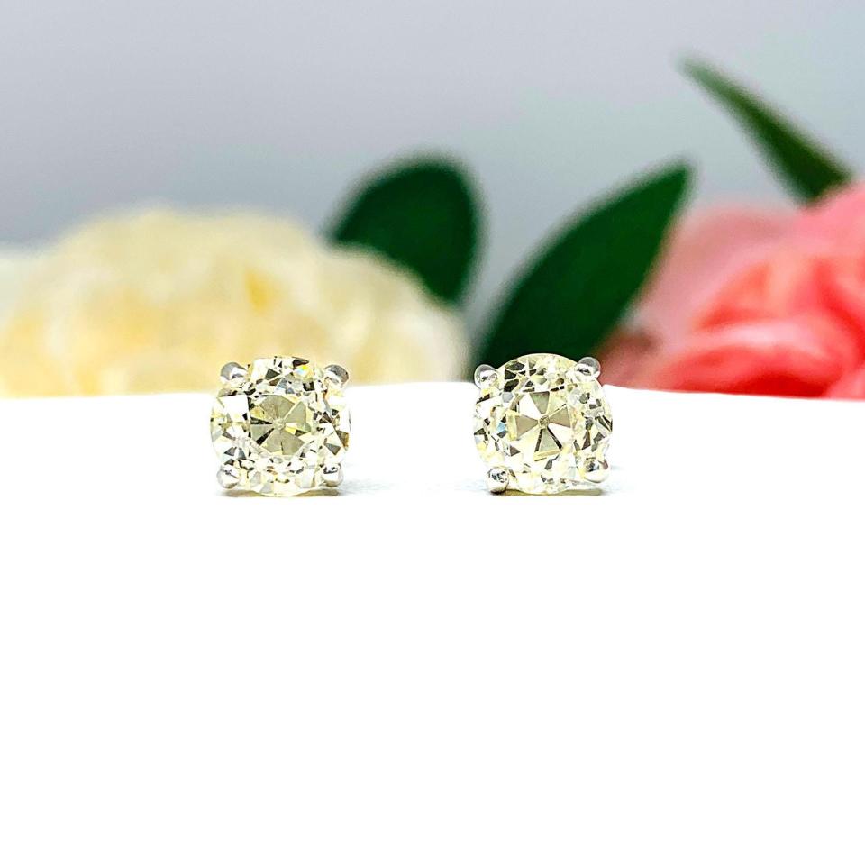 A pair of silver basket stud earrings set with light yellow old european cut round cubic zirconias.