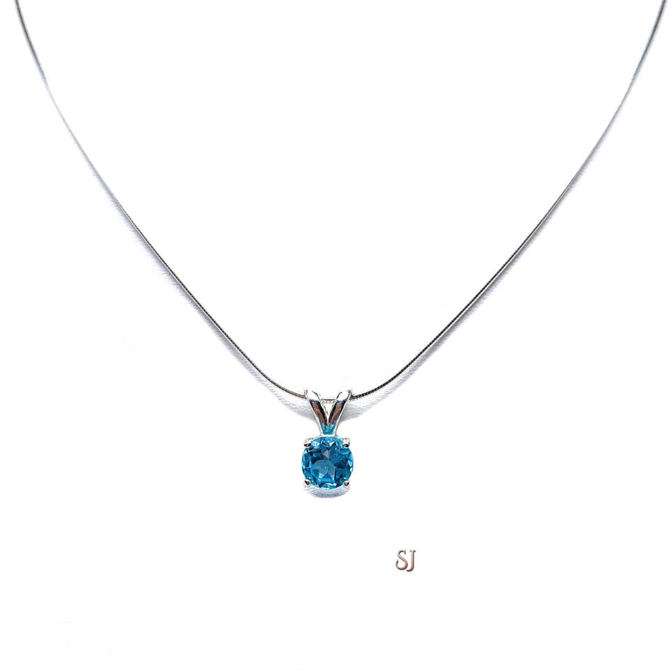 Sterling silver necklace featuring a natural 6mm round-cut swiss blue topaz pendant in a four-prong setting, shown on a sterling silver chain.