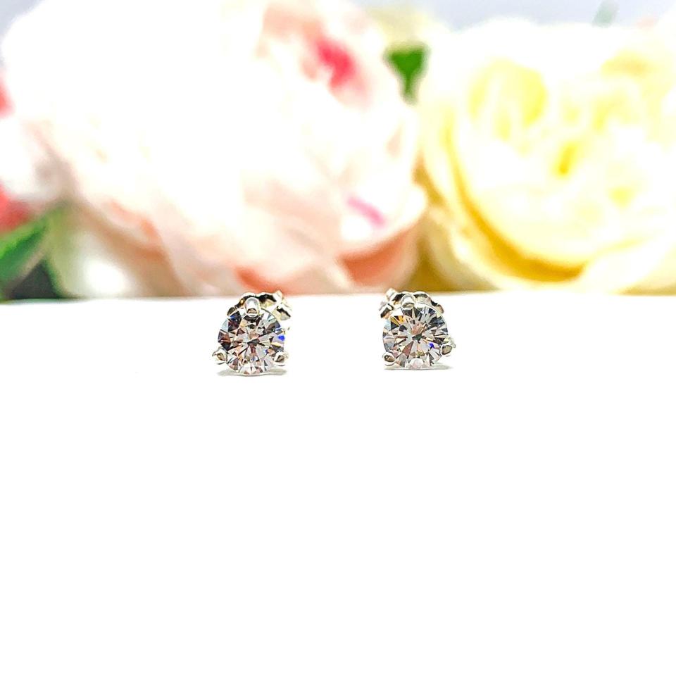 A pair of silver 3-prong basket martini round 'near colorless' or 'G color' cubic zirconia stud earrings. The earrings are shown on a white background with both earrings facing forward showcasing the crisp faceting and clear clarity of the czs.