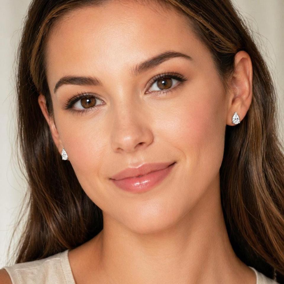 A woman wearing 9x6mm pear-cut cz 3-prong stud earrings. Model image for size and styling reference — not a photo of the actual earrings.