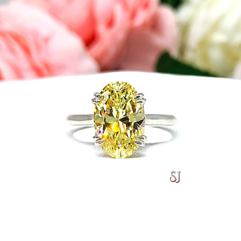 May include: A silver ring with a large, oval-shaped, yellow gemstone. The ring is set on a white background.