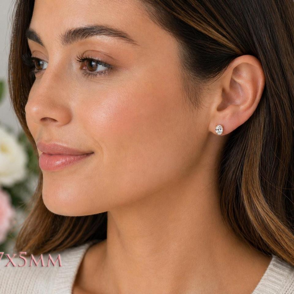 A woman wearing 7x5mm oval cz gold stud earrings. Model image for size and styling reference — not a photo of the actual earrings.