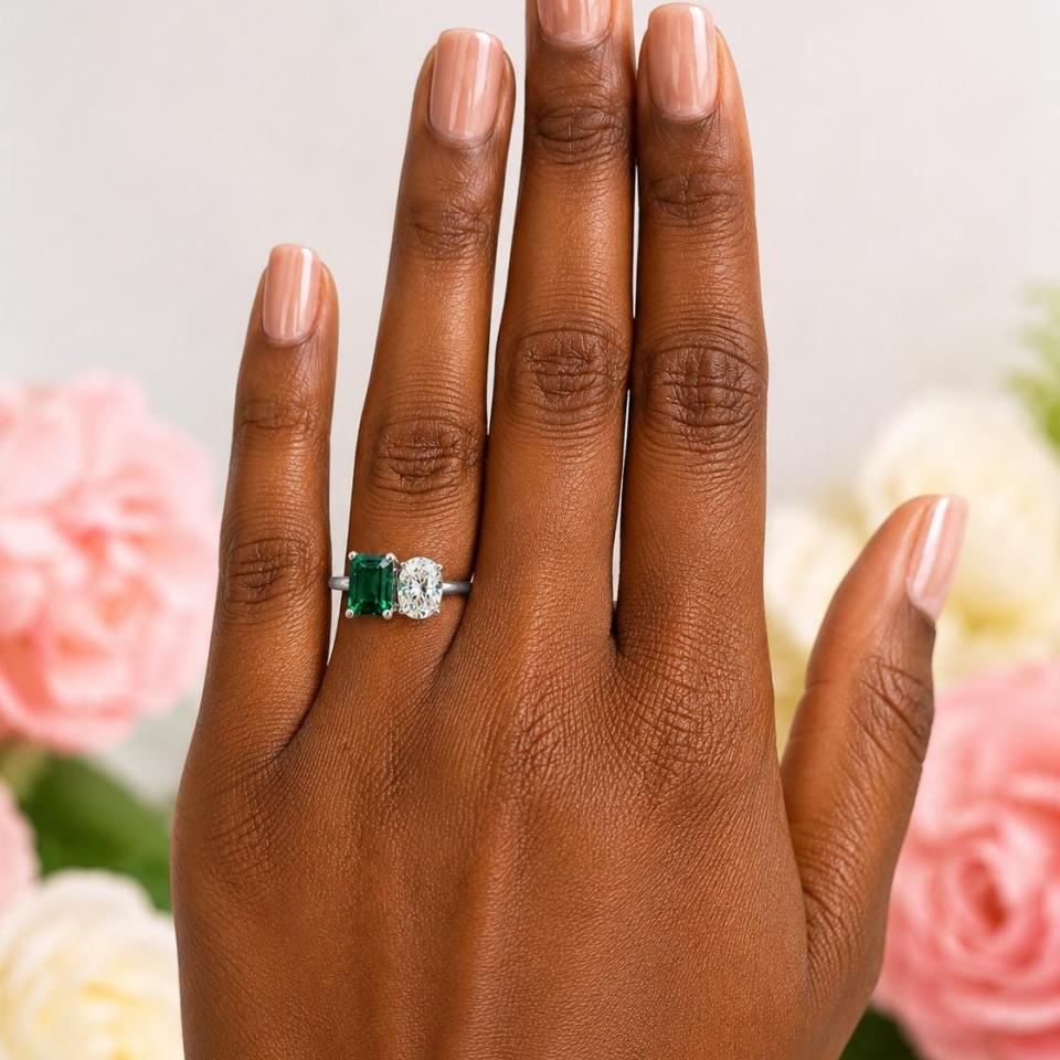 8x6mm emerald-cut lab emerald and 8x6mm oval‑cut CZ toi et moi ring in sterling silver shown worn on the hand of a woman. Model image for size and styling reference — not a photo of the actual ring.