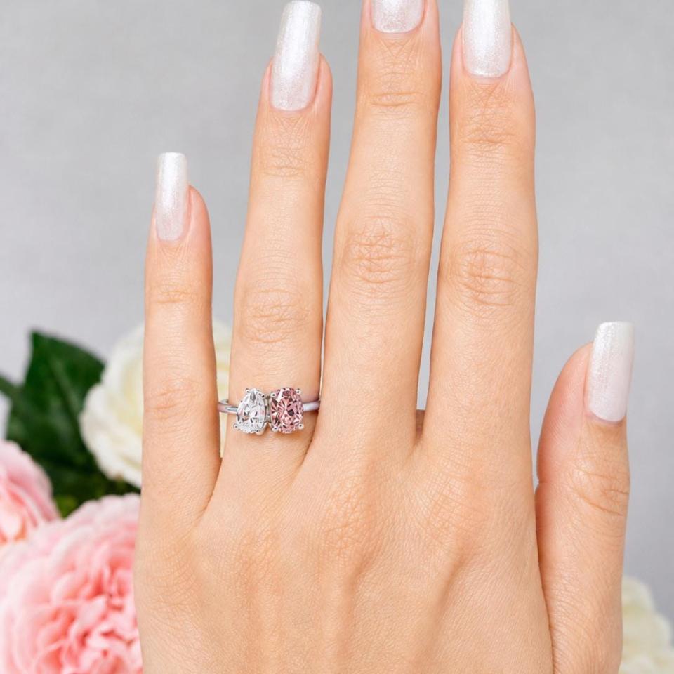 8x5mm colorless pear-cut CZ and an 8x6mm morganite pink color oval‑cut CZ toi et moi ring in sterling silver shown worn on the hand of a woman. Model image for size and styling reference — not a photo of the actual ring.
