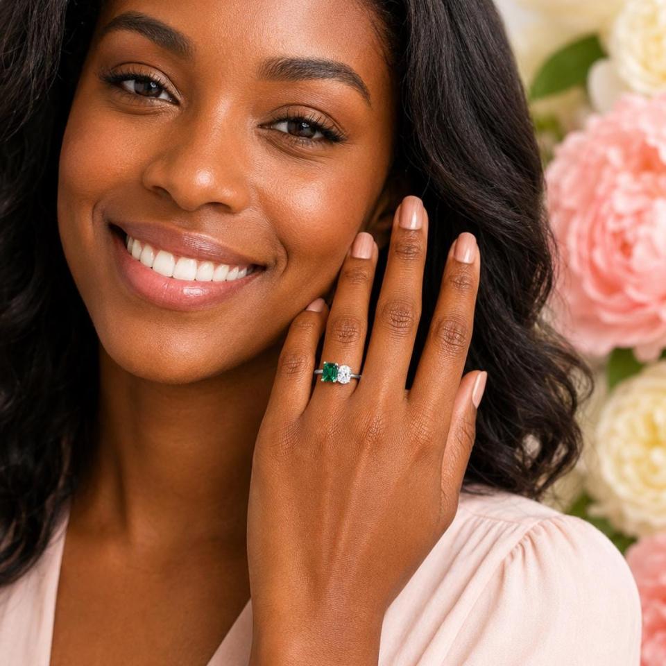 8x6mm emerald-cut lab emerald and 8x6mm oval‑cut CZ toi et moi ring in sterling silver shown worn on the hand of a woman. Model image for size and styling reference — not a photo of the actual ring.