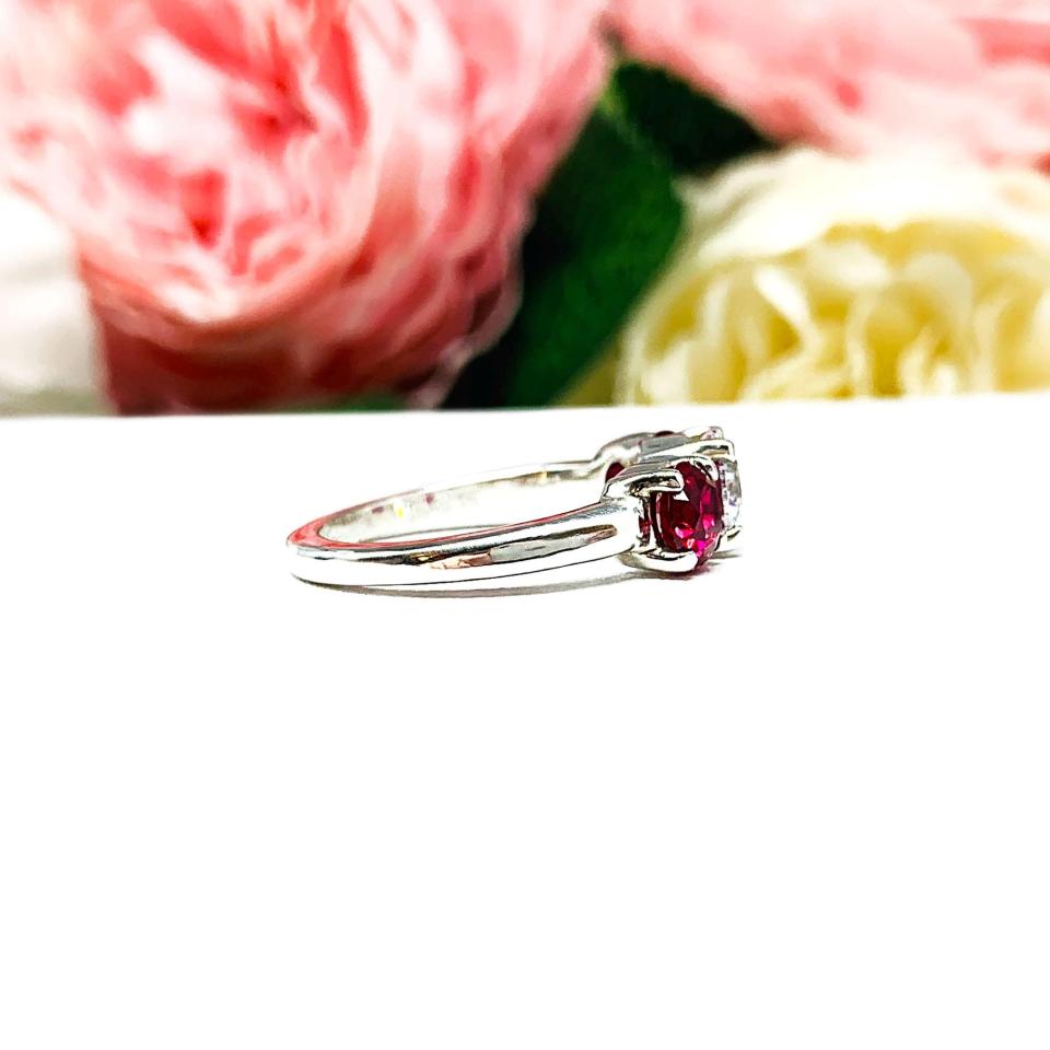 A sterling silver 3-stone ring with a 6mm round brilliant cut cubic zirconia center that radiates icy sparkle, flanked by two 5mm round deep red lab-created rubies.