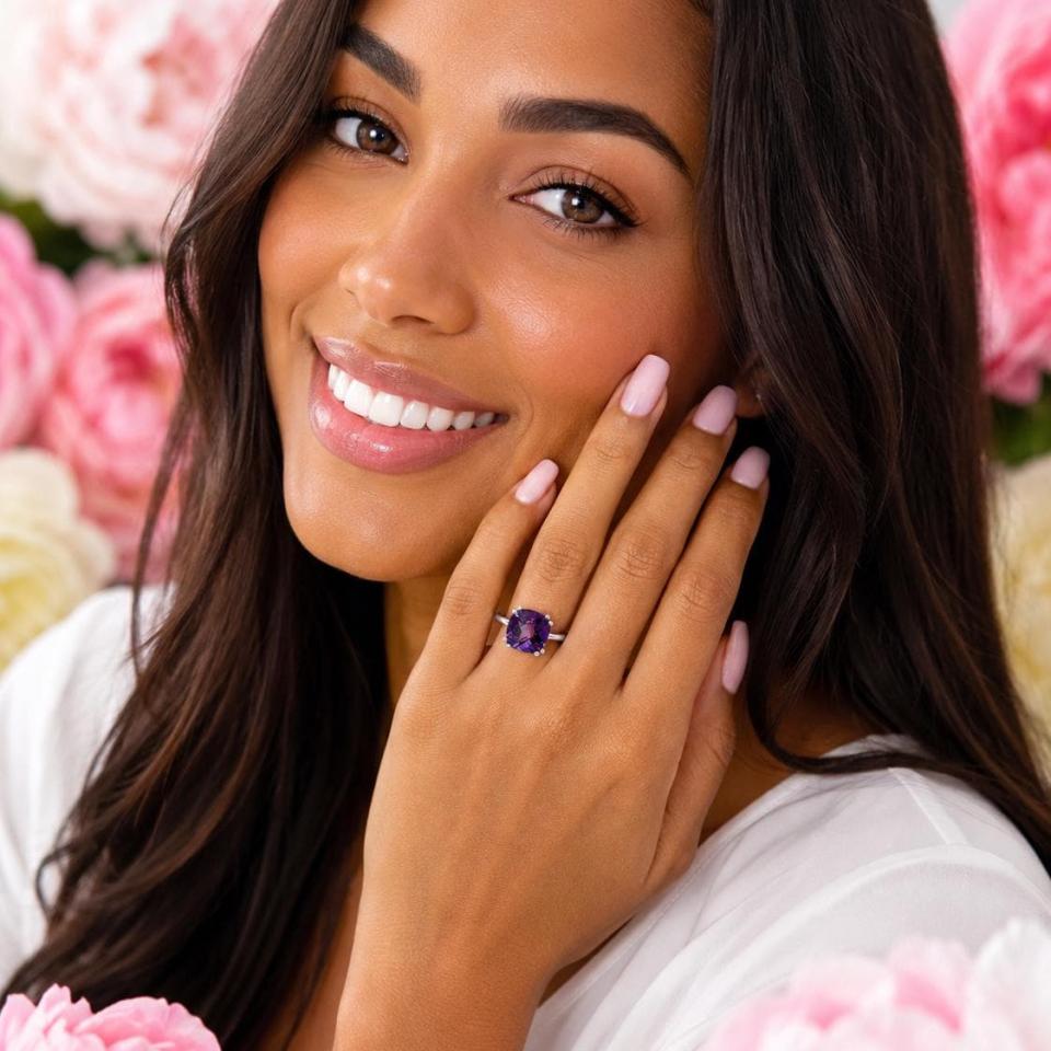 Sterling silver solitaire ring featuring a 10mm checkerboard cushion-cut African amethyst worn on a woman's hand. Model image for size and styling reference — not a photo of the actual ring.