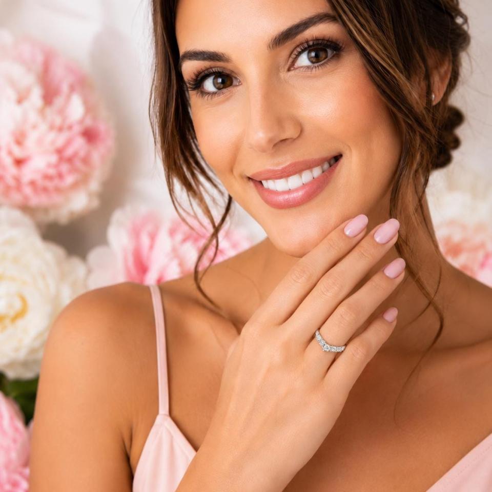 Woman wearing a curved sterling silver wedding band featuring five 3mm round near colorless czs. Model image for size and styling reference — not a photo of the actual ring