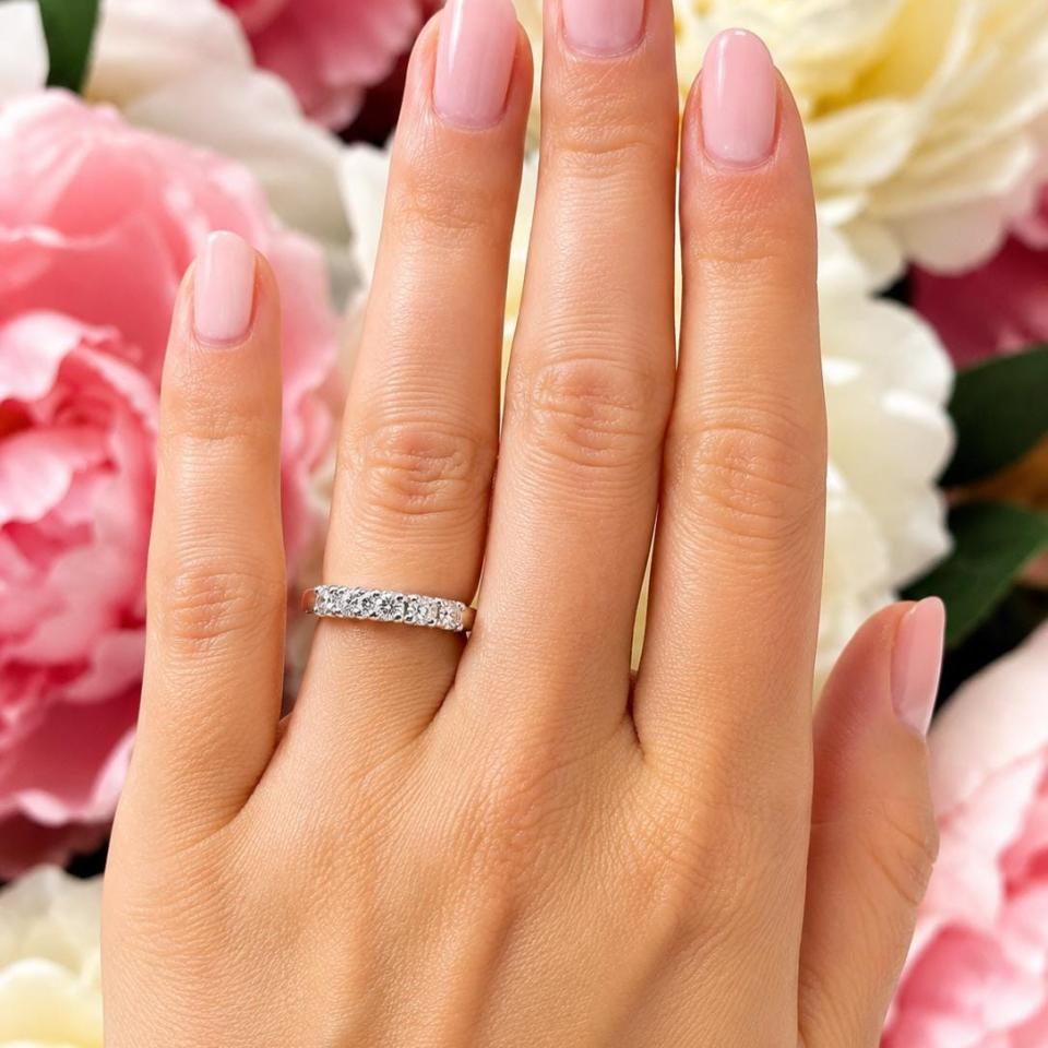 A woman's hand wearing a 5-stone wedding band featuring 3mm round moissanites.  Model image for size and styling reference — not a photo of the actual ring.