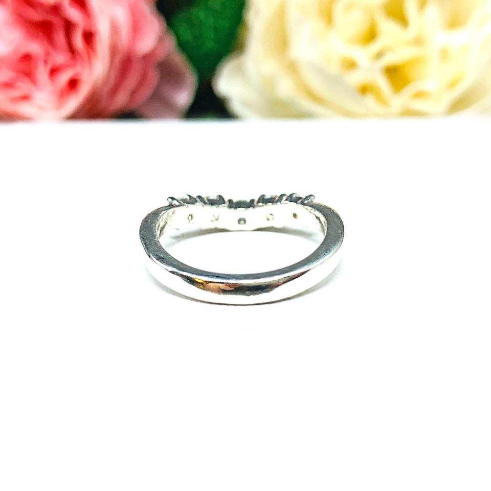 Sterling silver 5-stone curved wedding band featuring 3mm round precision faceted near colorless cubic zirconia stones in prong settings, displayed against a soft floral background.