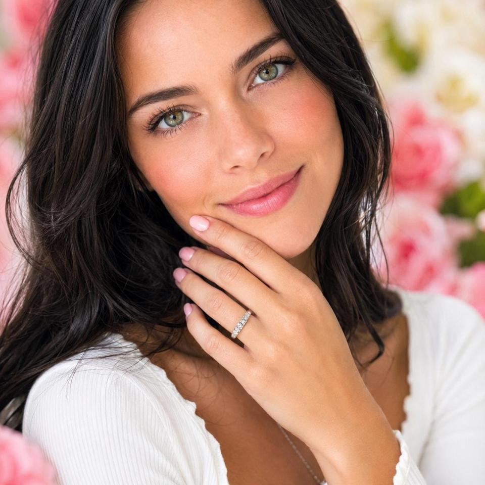A woman wearing a 5-stone wedding band featuring 3mm round moissanites.  Model image for size and styling reference — not a photo of the actual ring.