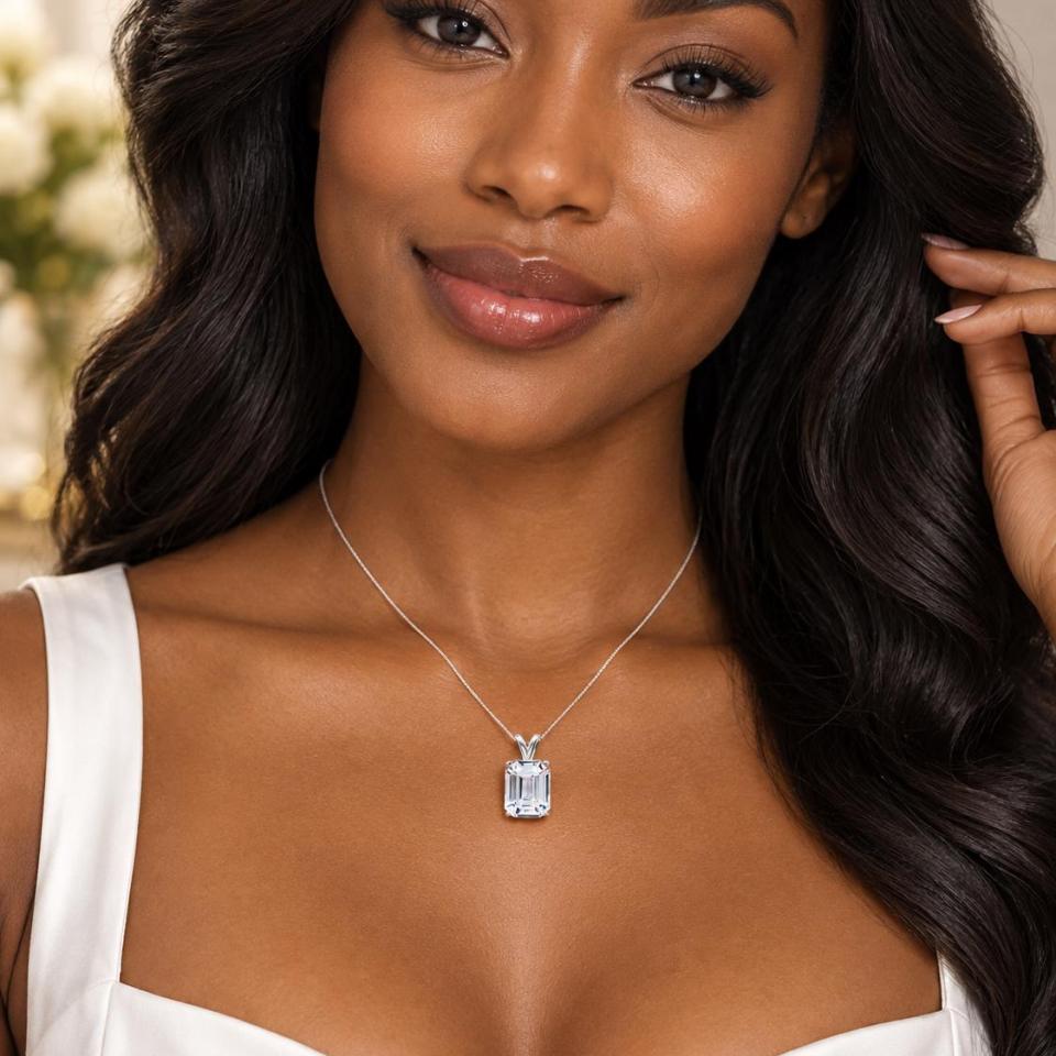A woman wearing a sterling silver necklace featuring a 12x10mm emerald-cut lab-created white sapphire pendant in a 4-prong setting. Model image for size and styling reference — not a photo of the actual necklace.