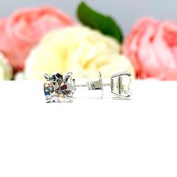 A pair of silver stud earrings with very light yellow or "near colorless" old mine cut cubic zirconia stones. The basket style soft claw prong earrings are on a white background with the left earring facing forward to showcase the 'chunky' facets and the right earring facing to the right displaying the center post and butterfly friction clasps.
