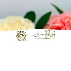 A pair of silver four prong basket stud earrings with light yellow modified Portuguese cut cubic zirconias. The earrings are on a white background with the left earring facing forward to showcase the dazzling brilliance of the Portuguese style faceting and the right earring facing to the right displaying the center post and butterfly friction clasps.