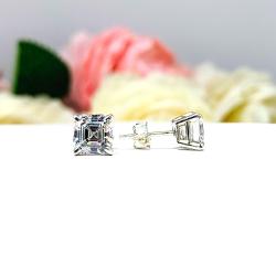 A pair of silver stud earrings with asscher cut clear cubic zirconia stones. The basket style soft claw prong earrings are on a white surface. The left earring is facing forward showcasing the crisp, clean and tight line facets and the left earring is facing toward the right displaying the center placed post and butterfly friction clasp.