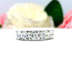 Five stone sterling silver ring featuring 5mm sparkling cushion cut cubic zirconias. Shown facing forward showcasing the "crushed ice"  faceting of the czs, shared prongs on each stone and highly polished band.