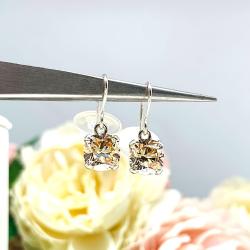 A pair of sterling silver 4-prong dangle earrings with cushion cut champagne cubic zirconia stones. Each dangle is suspended from a thin earwire that comes with a silicone back.