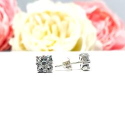 Sterling silver cluster earrings featuring four 3mm round light blue aquamarine gemstones. Displayed against a soft-focus floral background, the earrings sparkle with contrast and elegance.