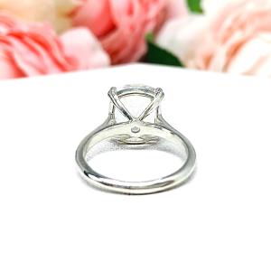 Sterling silver engagement ring featuring a sparkling elongated cushion-cut lab created white sapphire held in a split-prong setting, with soft-focus pink and white flowers in the background.